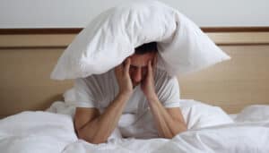 homme dans un lit qui n'arrive pas à dormir
